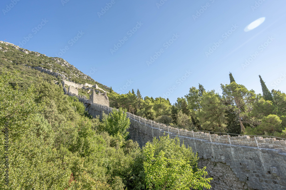 Fototapeta premium Narrow stone passage stairs on Wall of Ston aong hills in Croatia summer sunny morning