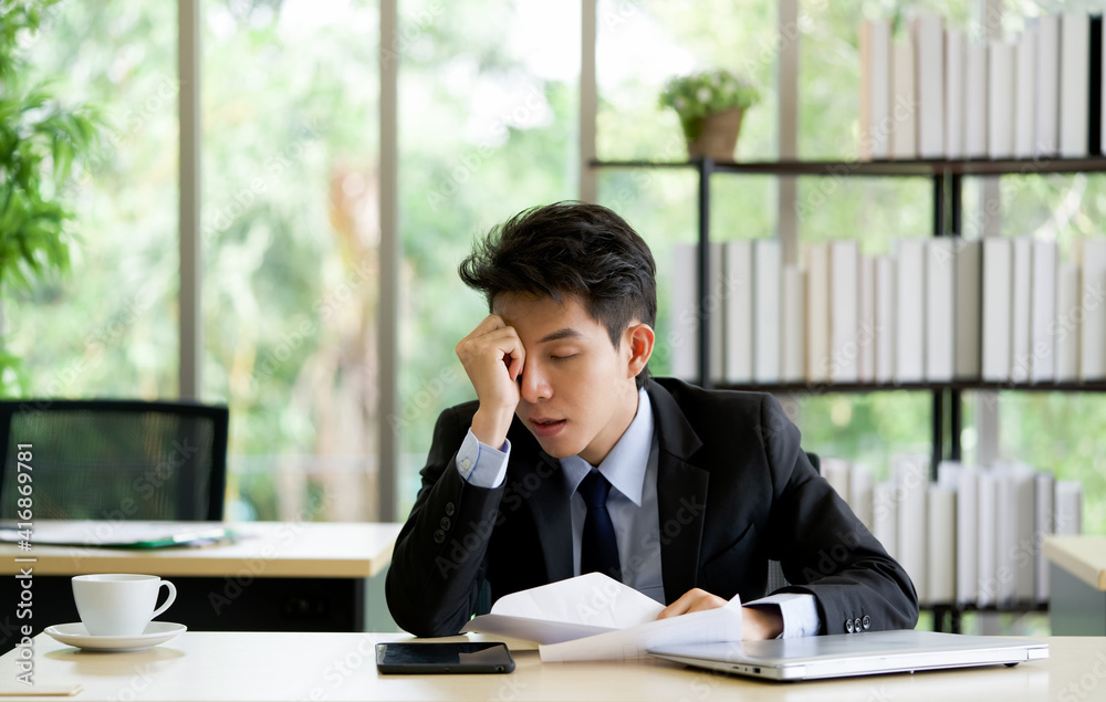 Young asian employee take a nap in the office on a table with tablet and laptop computer. Young asian employee take a nap in the office on a table with tablet and laptop computer.