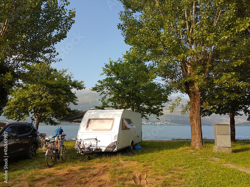 caravan car on the camping green grass and tress beside lake