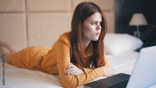 woman lies in bed in front of laptop emotions technology freelance