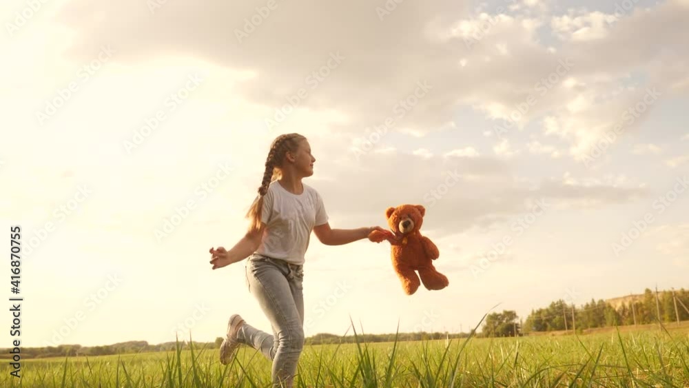 little girl with a teddy bear run in the park on the grass. happy family kid dream concept. little girl run in the park holding fun a teddy bear. happy childhood dream. kid walk in the park