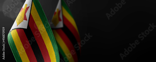Small national flags of the Zimbabwe on a dark background