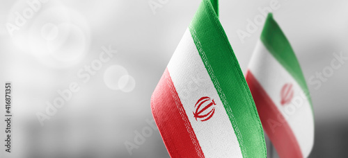 Small national flags of the Iran on a light blurry background