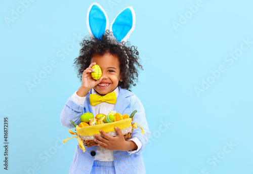 Canvas Print Funny little black child covering eye with Easter egg and smiling