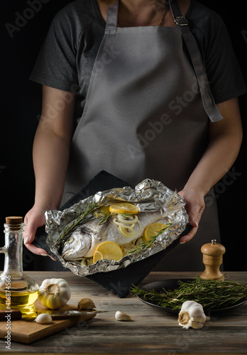 A dish with dorado fish baked in foil in the hands of the chef.