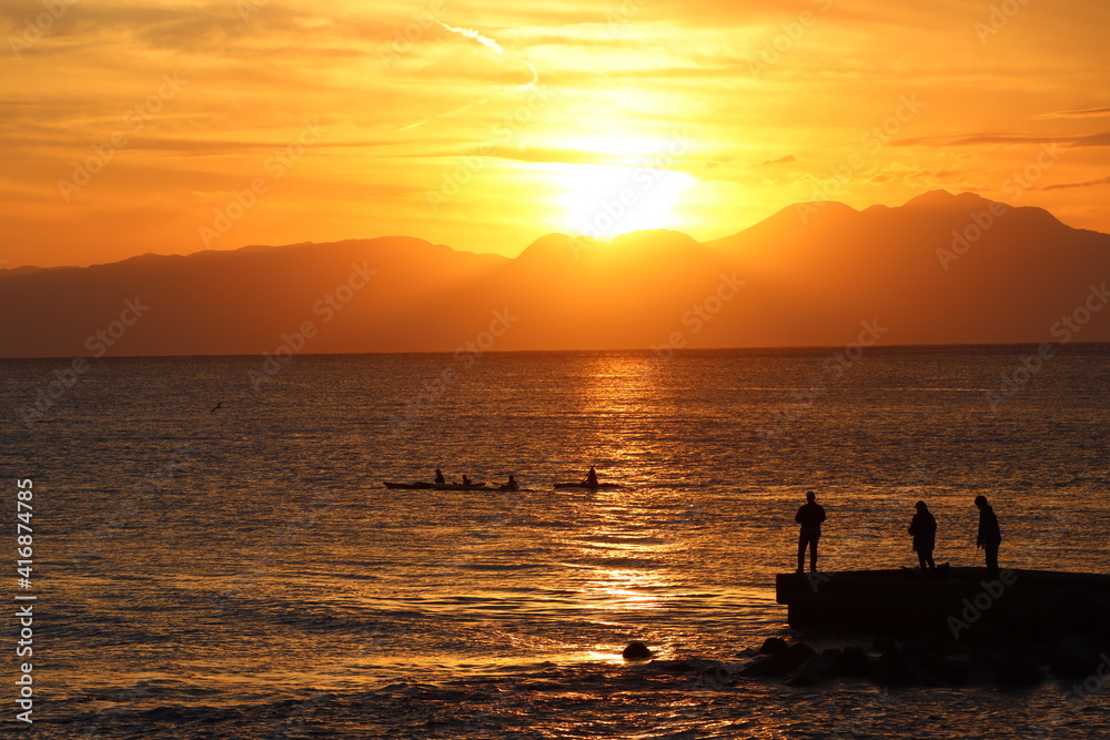 片瀬江ノ島海岸から見る伊豆半島に沈むオレンジ色の夕日と堤防のシルエット