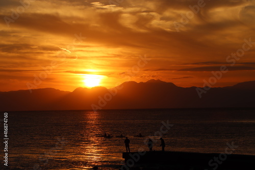 片瀬江ノ島海岸から見る伊豆半島に沈むオレンジ色の夕日と堤防のシルエット © acchity