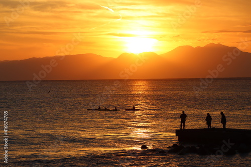 片瀬江ノ島海岸から見る伊豆半島に沈むオレンジ色の夕日と堤防のシルエット