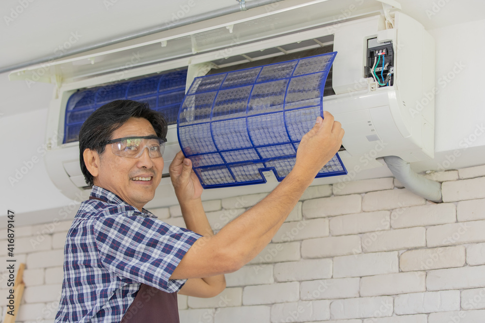 asian air conditioning mechanic wearing blue plaid shirt stand holding dirty filter full of dust smiling happily near white brick wall asian air conditioning mechanic wearing blue plaid shirt stand holding dirty filter full of dust smiling happily near white brick wall