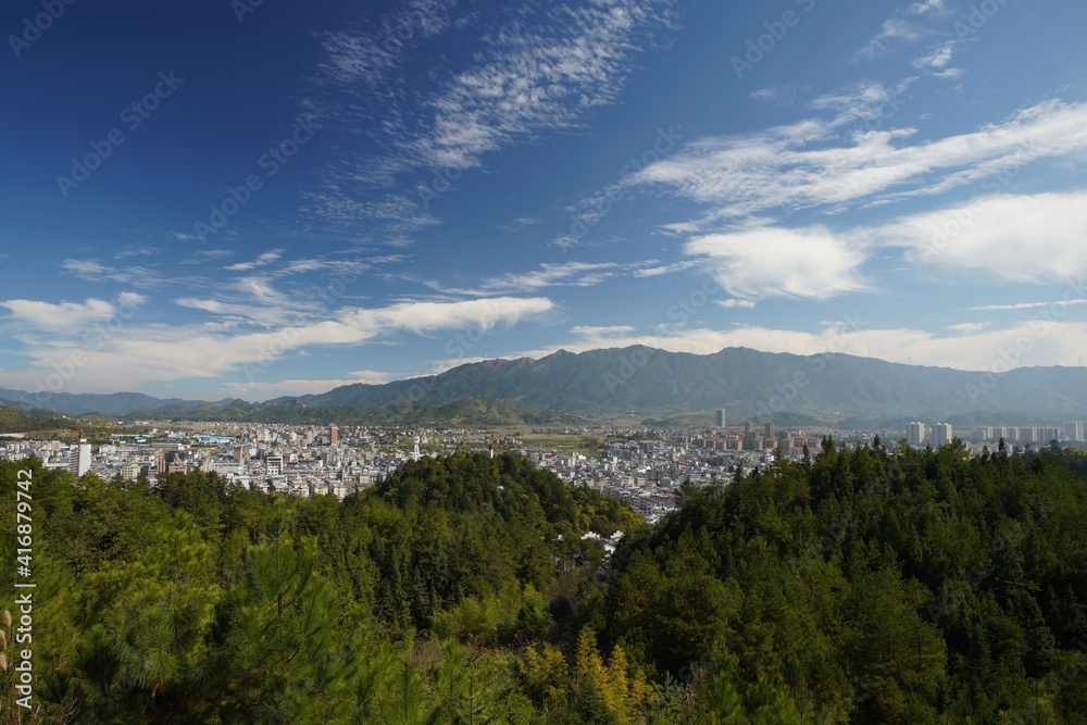 panorama of cityscape surrounded by green mountains; cityscape under the blue sky