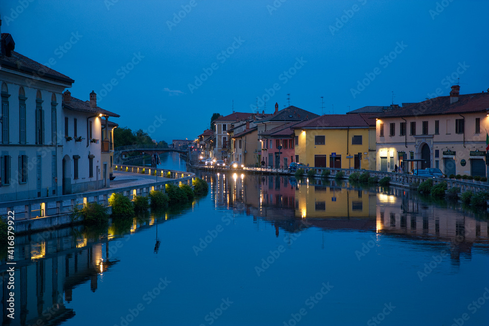 Beautiful colorful buildings on the water in Gaggiano, Italy with blue background