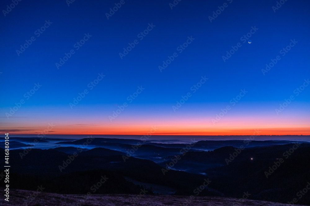 Beautiful scenery after sunset with a moon in the blue sky; shot on October 25, 2019 in Freiburg of Germany