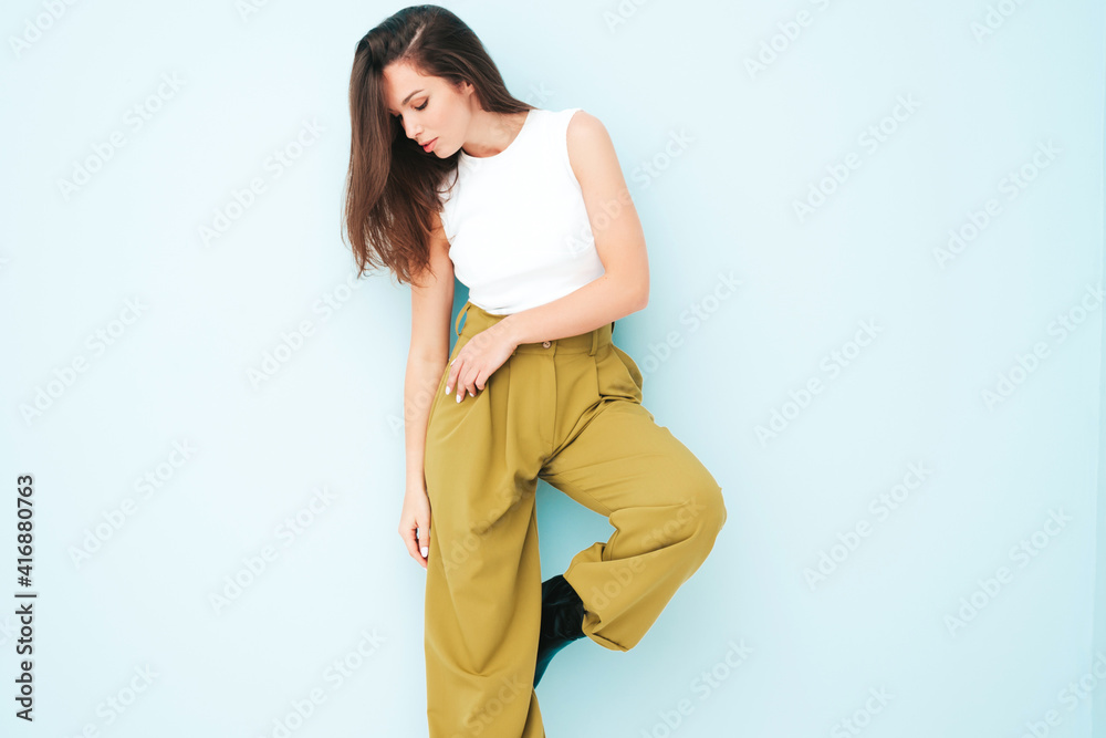 Young beautiful smiling female in trendy summer suit clothes. Sexy carefree woman posing near light blue wall in studio. Positive model having fun indoors. Cheerful and happy Young beautiful smiling female in trendy summer suit clothes. Sexy carefree woman posing near light blue wall in studio. Positive model having fun indoors. Cheerful and happy