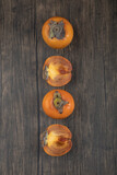 Whole and sliced fuyu persimmon fruits on wooden surface