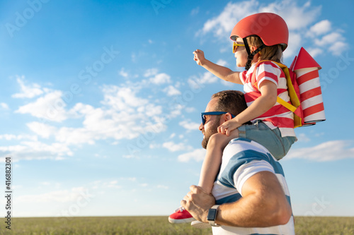 Father and son playing against blue summer sky background
