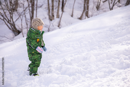 小さい男の子がスキー場にスキーウェアを着て立っている kids