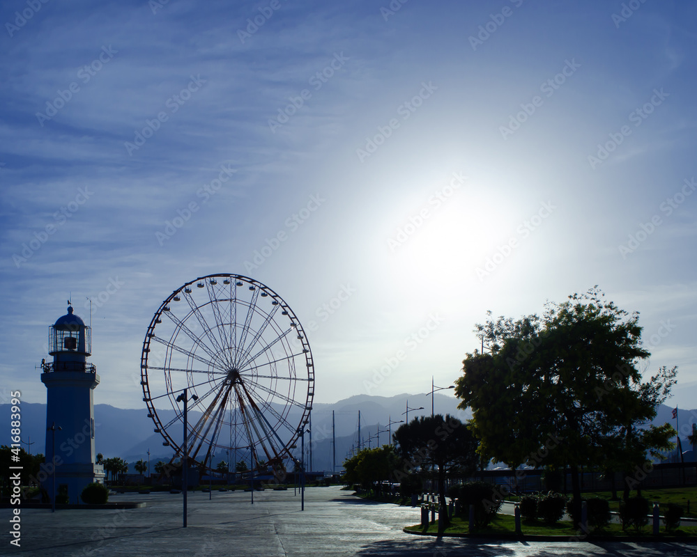 Batumi, Georgia - Ferris wheel and old Batumi lighthouse on the Batumi Seafront Promenade in the sunny day