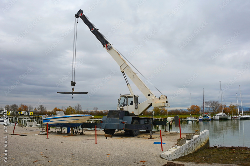 A hydraulic mobile suspended boat lift or hoist with a sling. Located in an out-of-season marina in northern Italy

