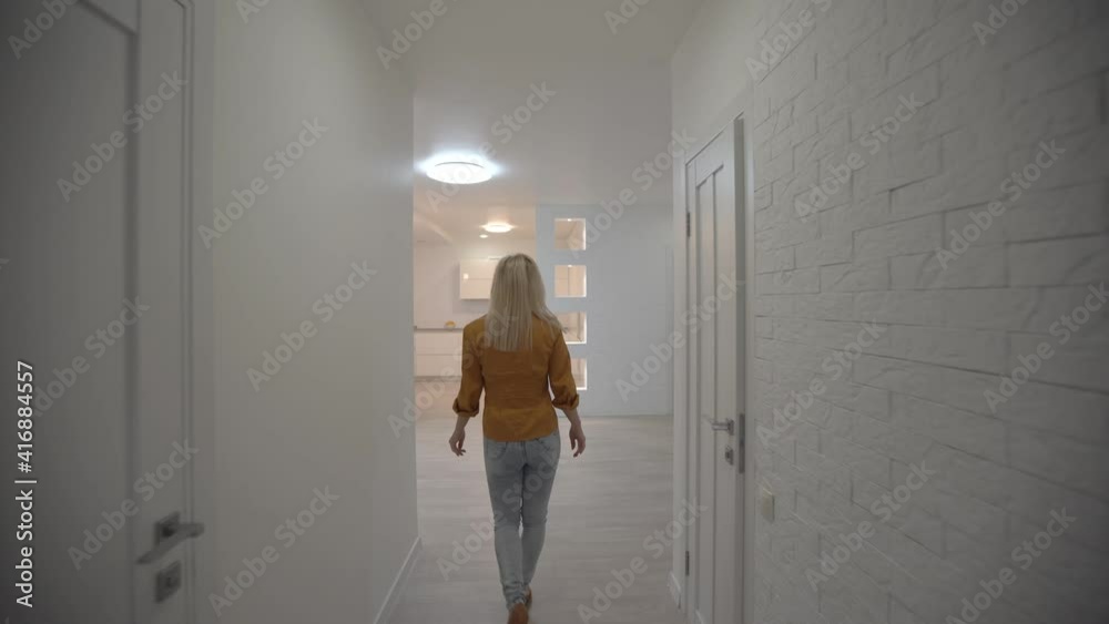 Moving in new apartment, woman with keys walks into her new flat, empty white rooms, new home construction. Moving in new apartment, woman with keys walks into her new flat, empty white rooms, new home construction.
