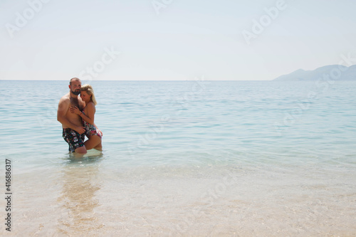 Loving couple enjoying honeymoon on beach in laguna with luxury view walking on sea background. Happy lovers on romantic trip have fun on summer vacation. Concept romance and relaxation. Copy space