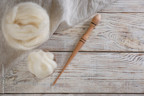Soft wool and spindle on white wooden table, flat lay. Space for text
