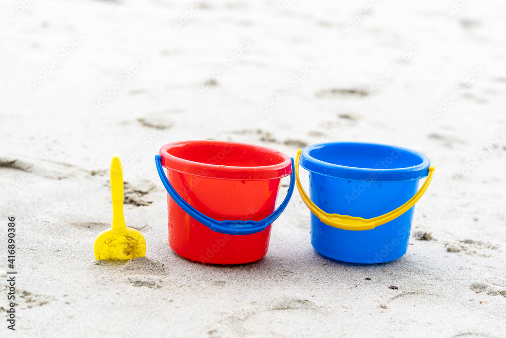 Children's beach toys - buckets, spade and shovel on sand on a sunny day Children's beach toys - buckets, spade and shovel on sand on a sunny day