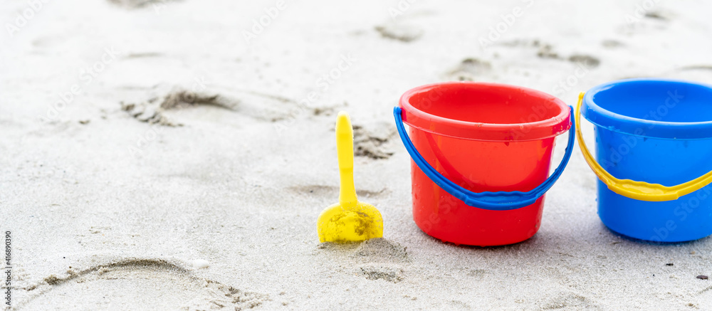 Children's beach toys - buckets, spade and shovel on sand on a sunny day Children's beach toys - buckets, spade and shovel on sand on a sunny day