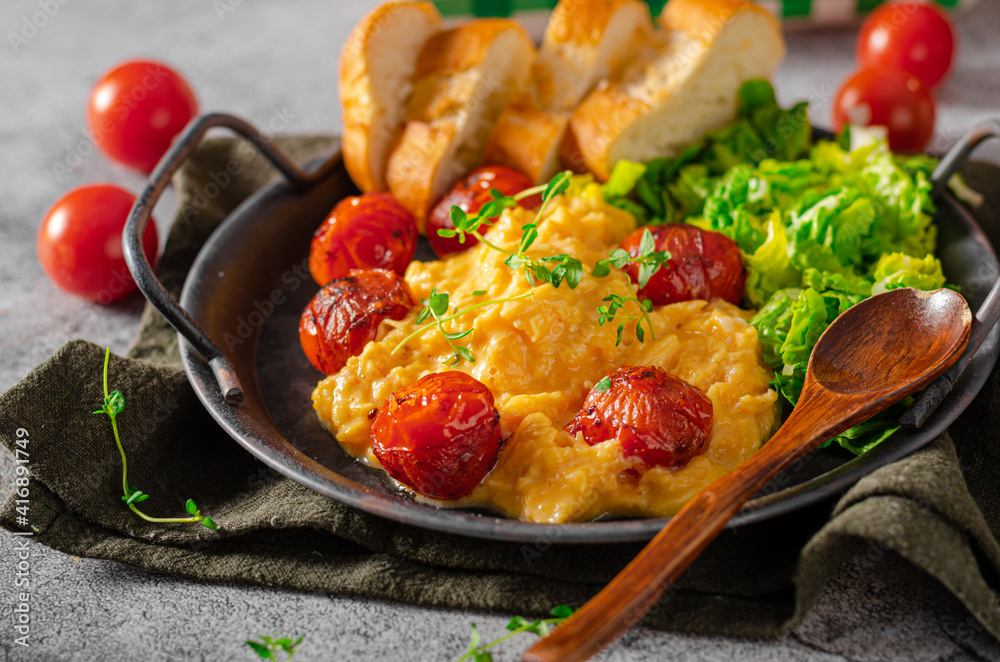 Scrambled eggs with salad and grilled tomatoes