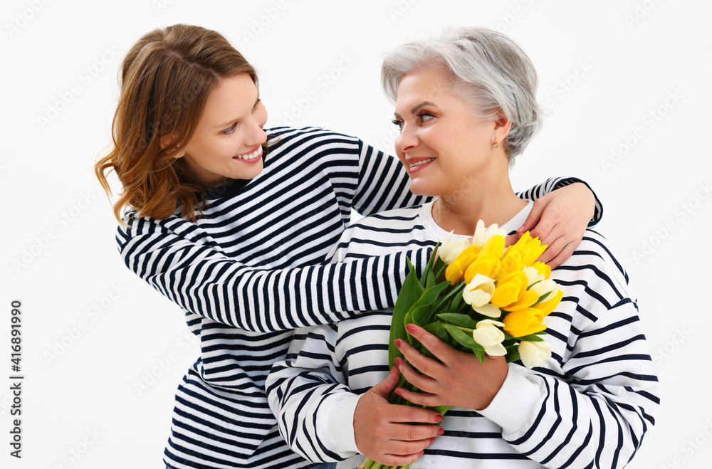 Happy senior woman with bunch of tulips smiling in studio with young daughter Happy senior woman with bunch of tulips smiling in studio with young daughter