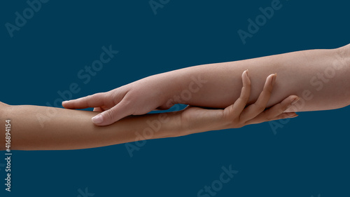 Close up of two women holding each other arm isolated on blue background