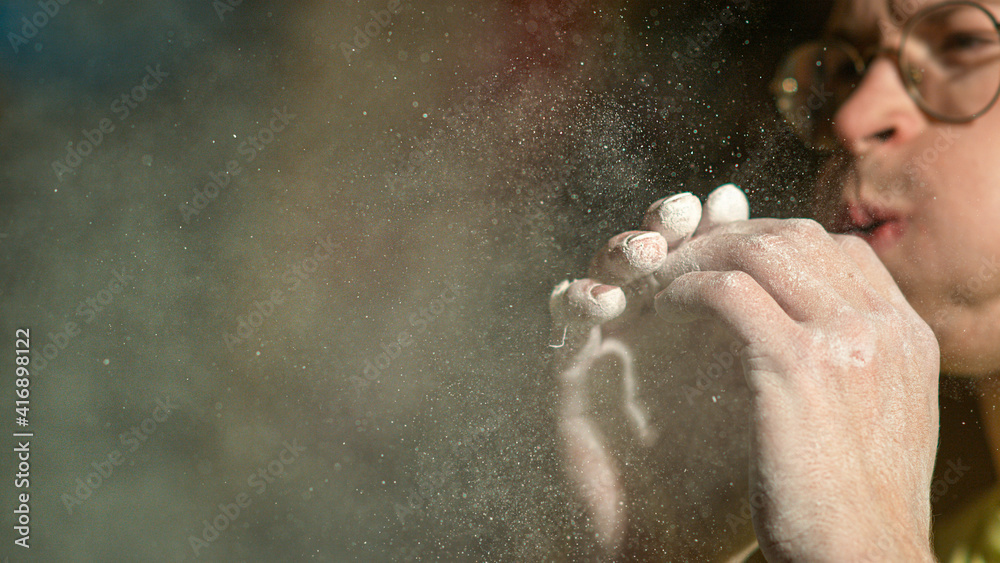 CLOSE UP: Man climbing indoors blows into palms and removes magnesium powder. CLOSE UP: Man climbing indoors blows into palms and removes magnesium powder.