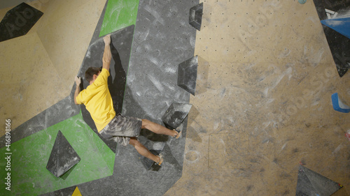 Unrecognizable young male climber trains indoors in the winter.