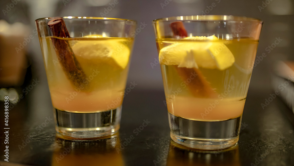 Two cocktails of whiskey, rum, lemon or brandy with cinnamon on the bar Two cocktails of whiskey, rum, lemon or brandy with cinnamon on the bar