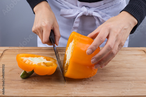 Cutting board with knife and fresh bell pepper.
