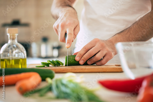 Close up photo of young male hands is preparing wonderful fresh vegan salad in the kitchen at home