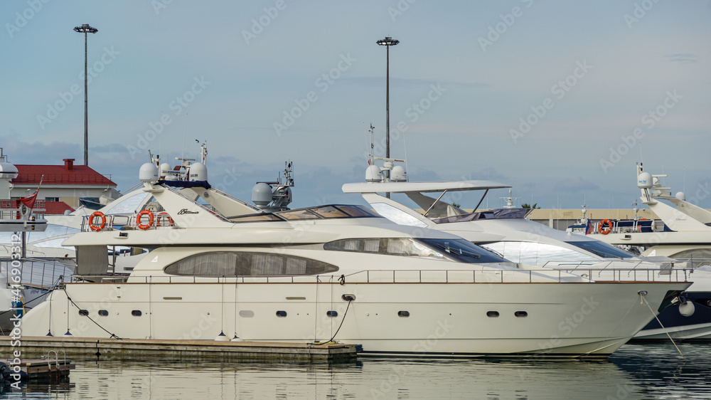 Fototapeta premium Ships, yachts and boats on blue surface of Black Sea by pier of Commercial seaport of Sochi. Resort city center. Sochi, Russia - November 23, 2020
