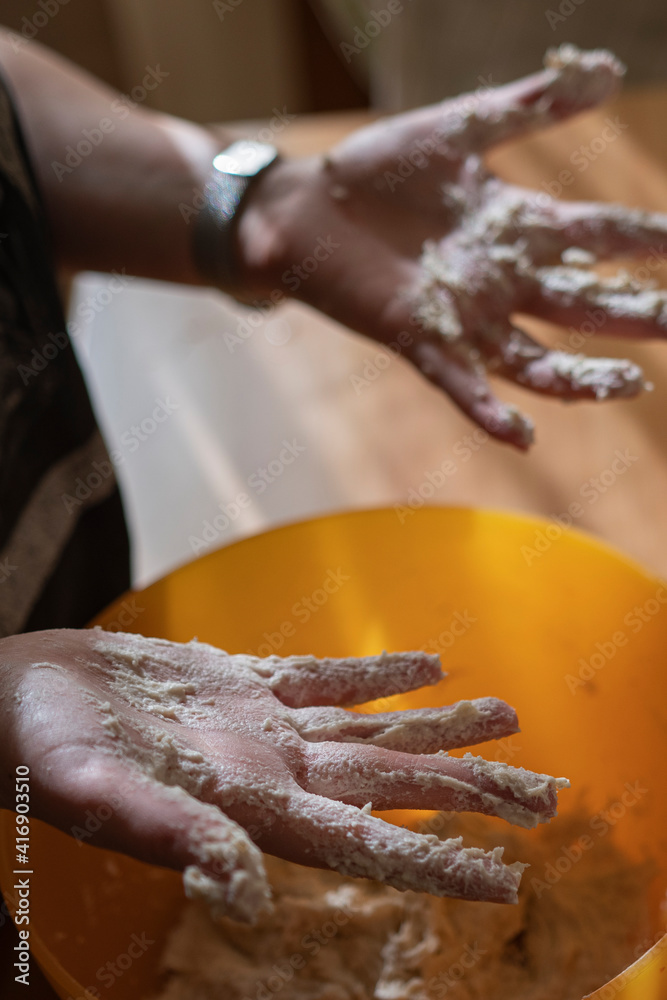 Close up of feminine hands mixing flour and water to make dough