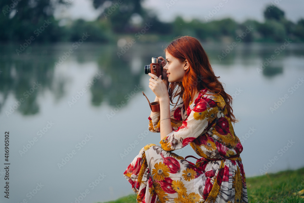 woman in a multicolored dress with a camera in her hands outdoors