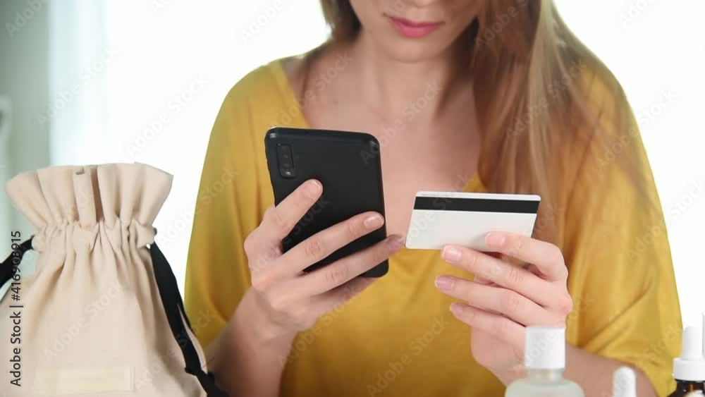 Woman holding credit card making e bank online payment. Buying cosmetics online from home Woman holding credit card making e bank online payment. Buying cosmetics online from home