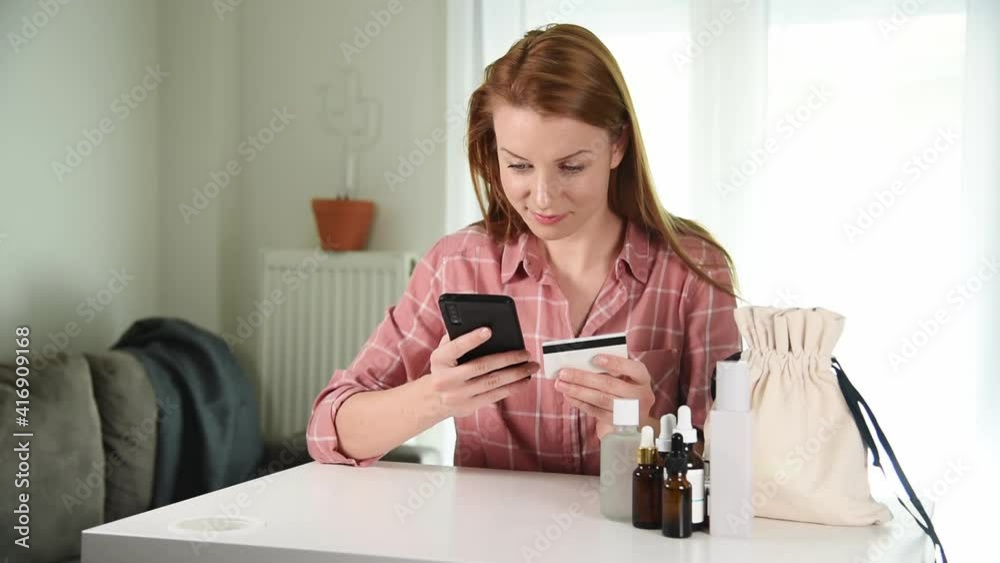 Woman holding credit card making e bank online payment. Buying cosmetics online from home Woman holding credit card making e bank online payment. Buying cosmetics online from home