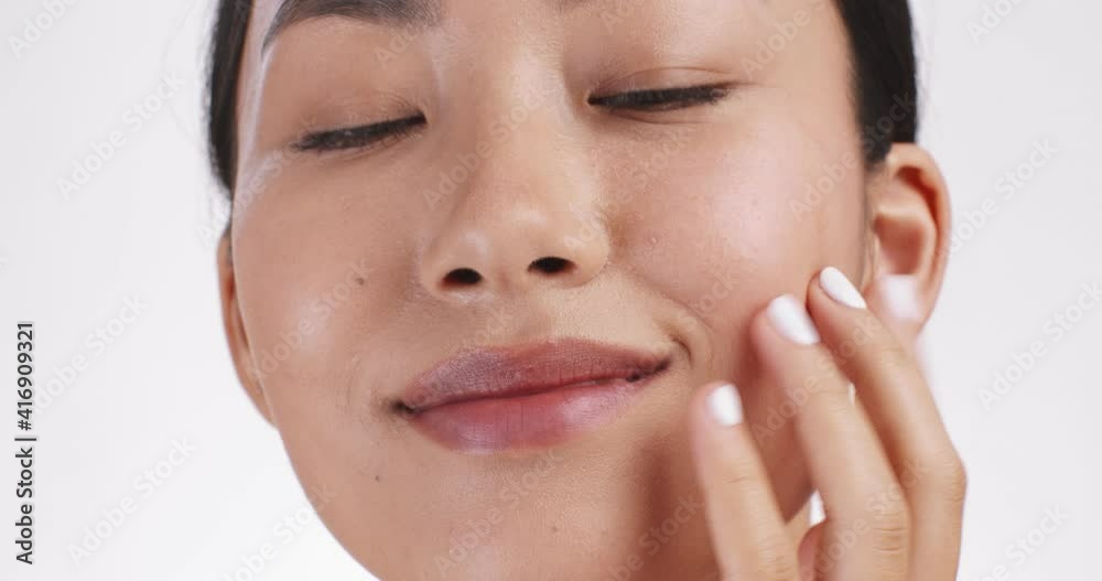 Face lifting massage. Young asian woman massaging her face for lymphatic drainage effect, white studio background