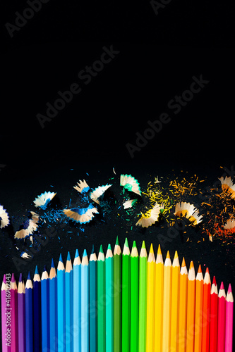 Colored watercolor pencils on a black background. Sharpening pencils. Vertical picture