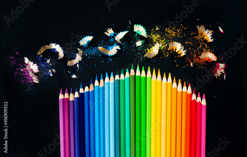Colored watercolor pencils on a black background. Sharpening pencils. Horizontal picture