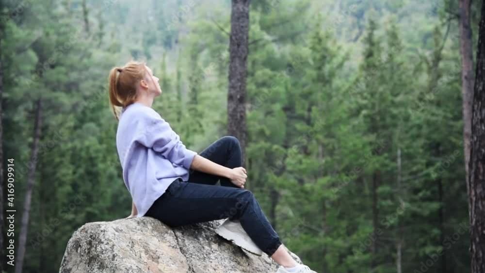 Young beautiful woman sitting on the huge rock in forest with soft natural lighting. Young beautiful woman sitting on the huge rock in forest with soft natural lighting.