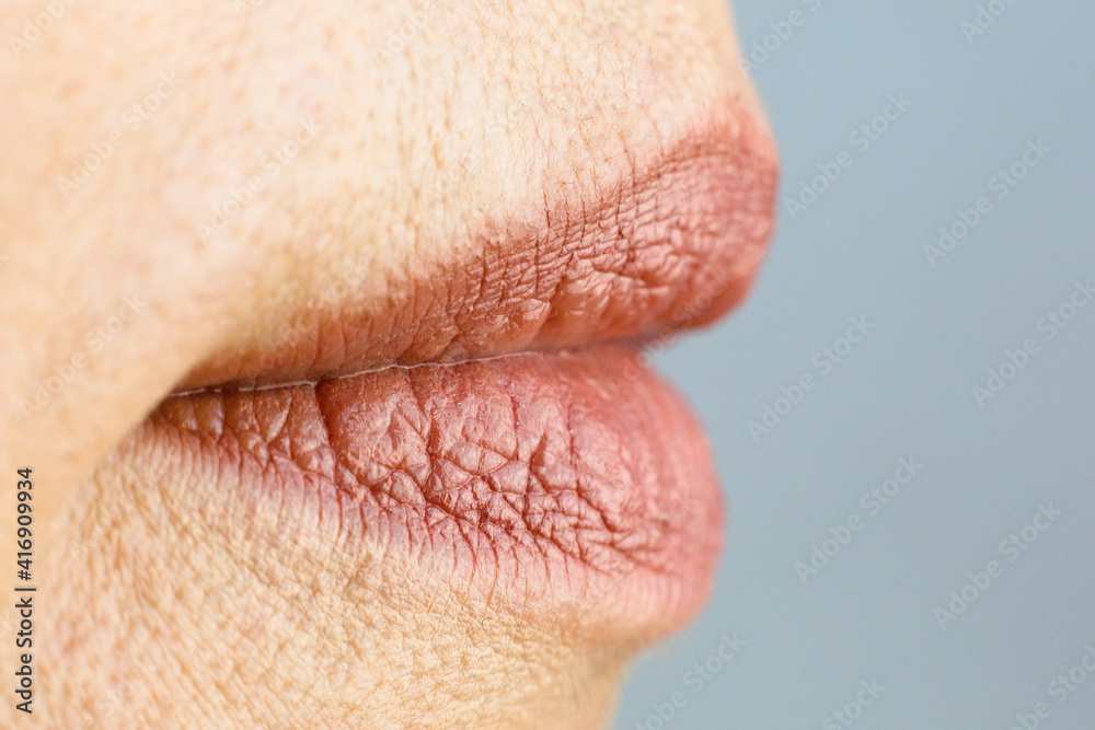 Lipstick painted female lips on a gray background. Close-up. Lipstick painted female lips on a gray background. Close-up.