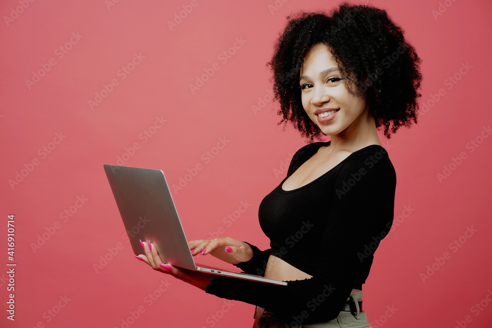 writes a message. the programmer holds a laptop in his hands. Positive mood. young woman of Afro appearance, curly lush hair. She is dressed in a black comfortable jacket. Copy space. writes a message. the programmer holds a laptop in his hands. Positive mood. young woman of Afro appearance, curly lush hair. She is dressed in a black comfortable jacket. Copy space.