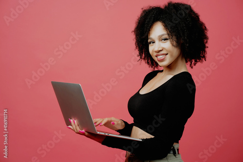 writes a message. the programmer holds a laptop in his hands. Positive mood. young woman of Afro appearance, curly lush hair. She is dressed in a black comfortable jacket. Copy space.