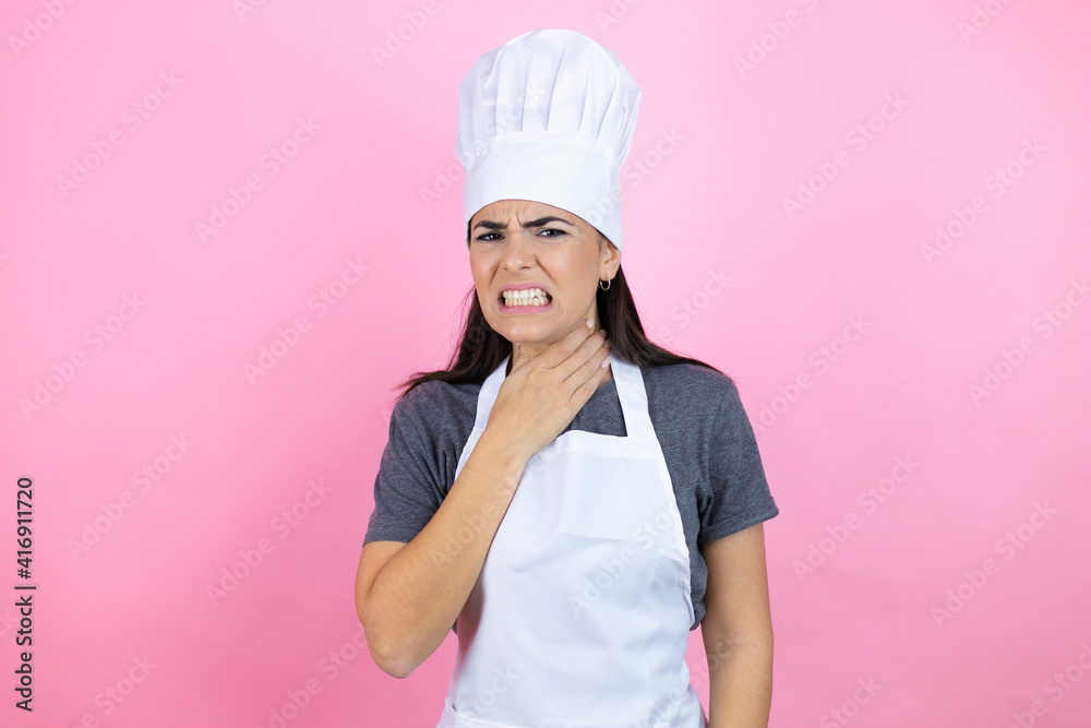 Young hispanic woman wearing baker uniform over pink background touching painful neck, sore throat for flu, clod and infection Young hispanic woman wearing baker uniform over pink background touching painful neck, sore throat for flu, clod and infection