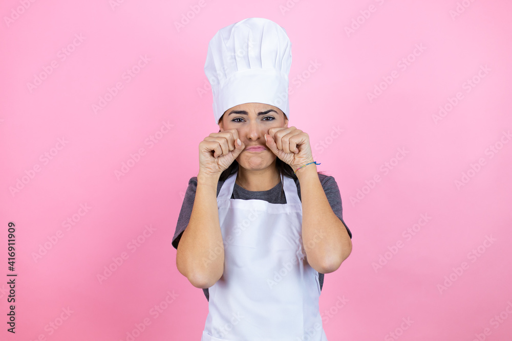 Young hispanic woman wearing baker uniform over pink background depressed and worry for distress, crying angry and afraid. Sad expression. Young hispanic woman wearing baker uniform over pink background depressed and worry for distress, crying angry and afraid. Sad expression.