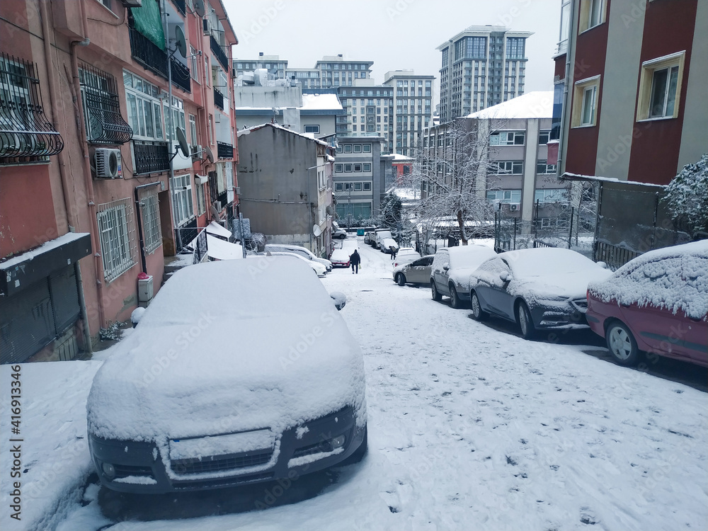 town street and cars covered by snow in winter time after heavy snowfall